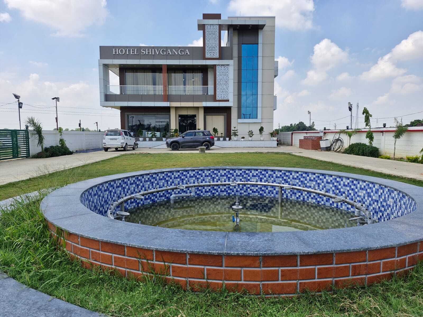 Un hotel chiamato 'HOTEL SHIVGANGA' dal design moderno, con piscina e area parcheggio.