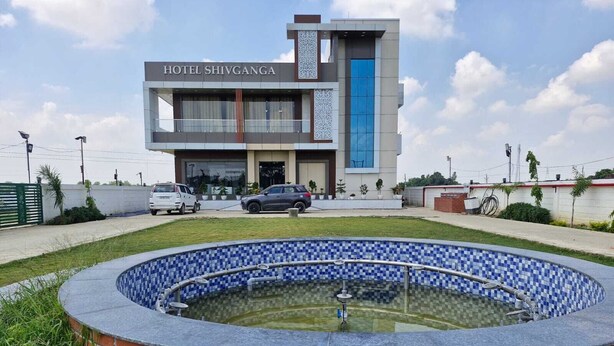 Een hotel genaamd 'HOTEL SHIVGANGA' met een modern design, een zwembad en een parkeerplaats.