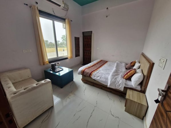 Una habitación de hotel con cama, una silla, una mesita y una ventana con cortinas.