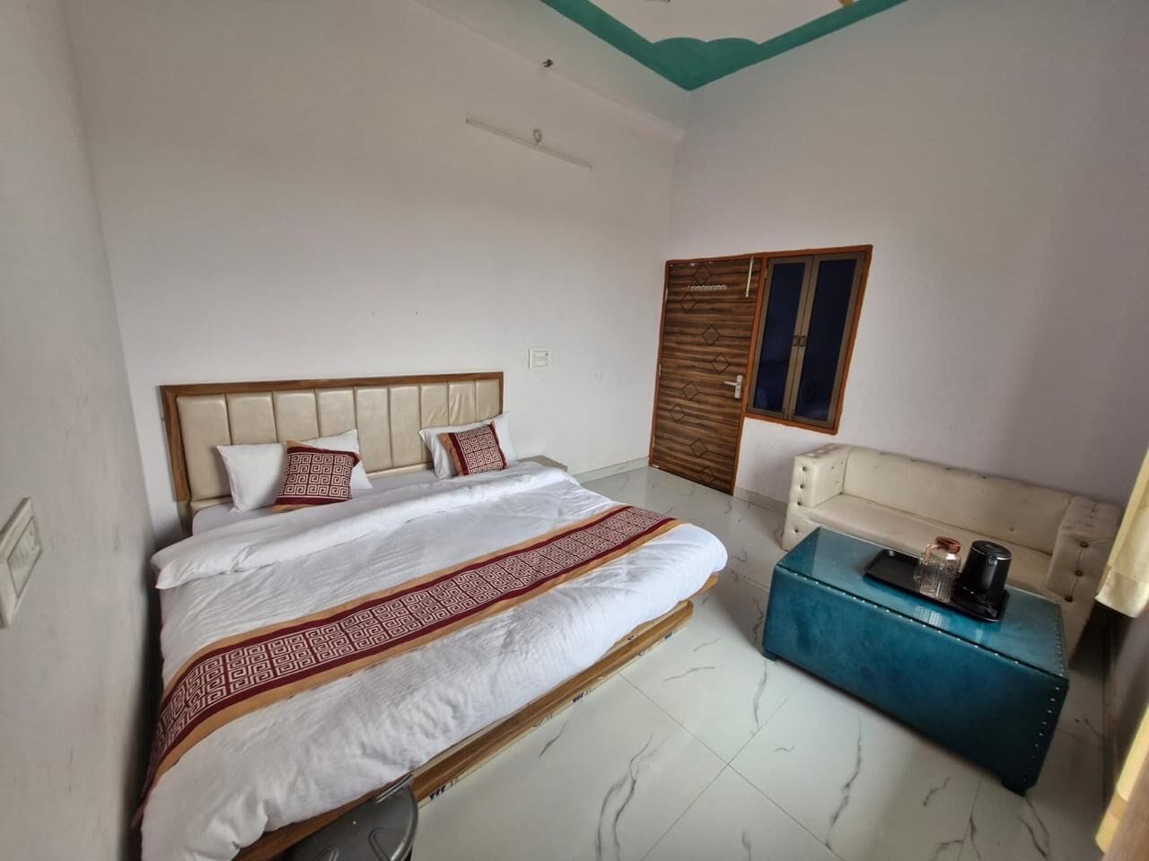 A bedroom with a bed, a sofa, a chest of drawers, and a wardrobe.