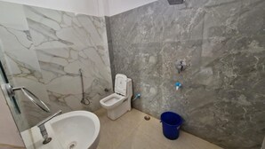 Een badkamer met een marmeren wastafel, toilet en een blauwe emmer.