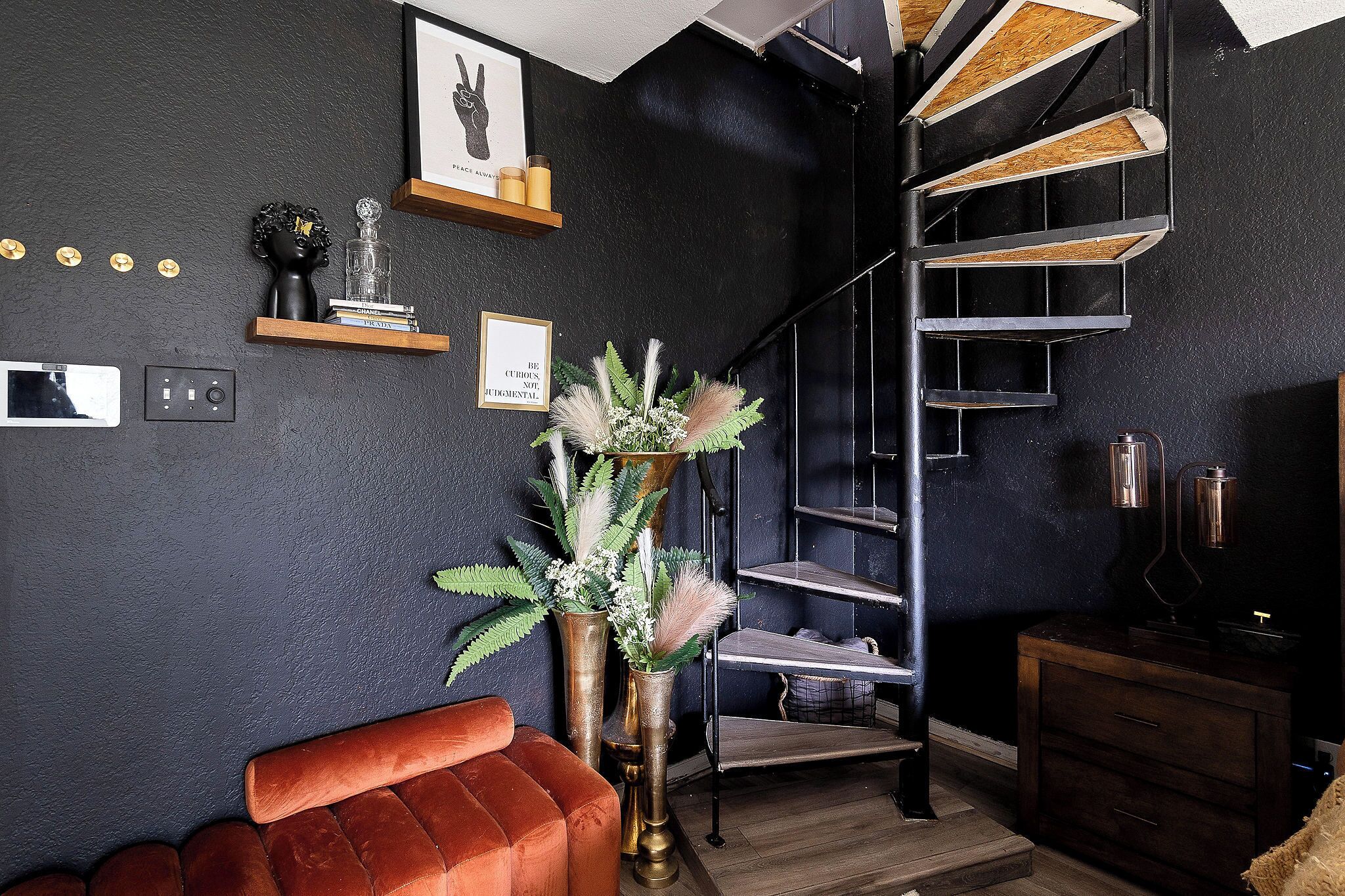 Un interior moderno con una escalera espiral, un sofá rojo y elementos decorativos en las paredes.