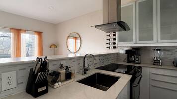 A modern kitchen with a double sink, a coffee maker, and wine bottles on the wall.