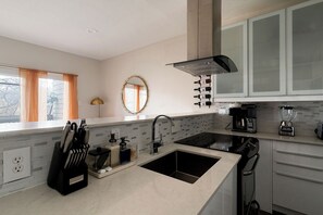 A modern kitchen with a double sink, a coffee maker, and wine bottles on the wall.