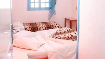 Un dormitorio con cama, ventana con cortinas, aire acondicionado y mesita de noche.