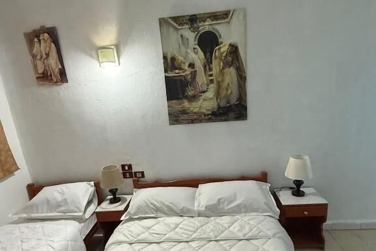 Een hotelkamer met twee bedden, een schilderij aan de muur en een lampje op het nachtkastje.