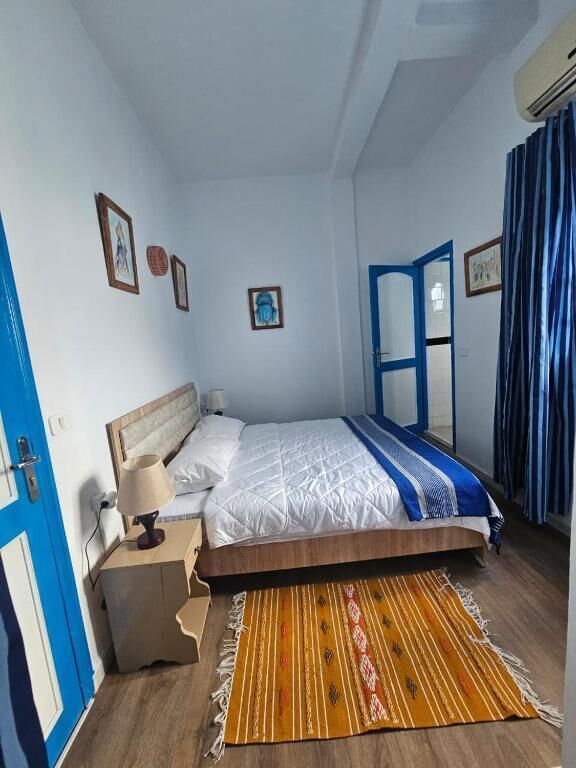 A bedroom with a bed, bedside table, and a window with curtains.