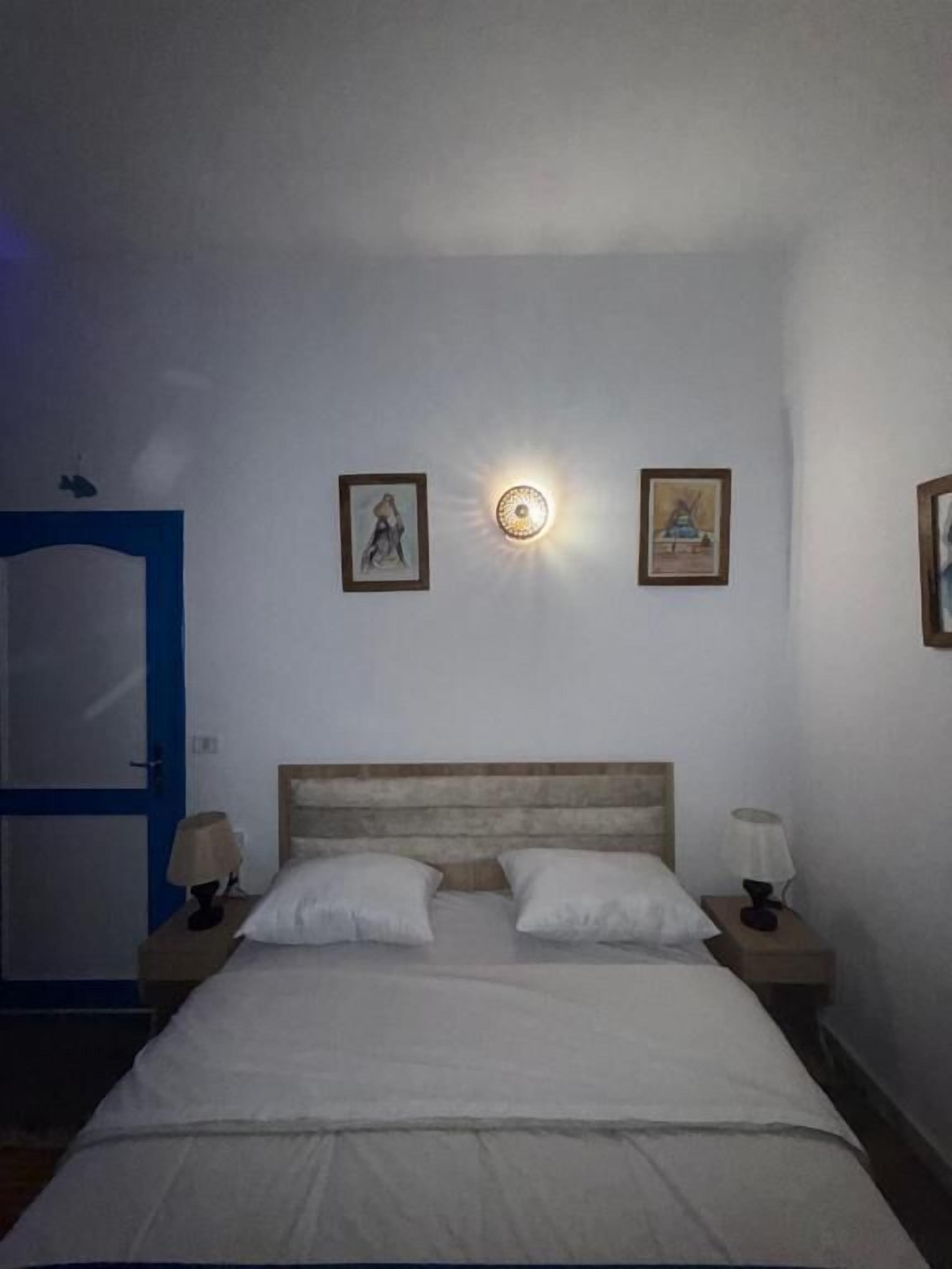 Un dormitorio con una cama, dos lámparas de noche y dos luces fijadas a la pared.