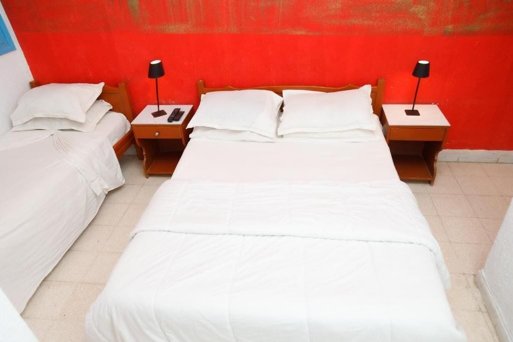 A hotel room with two single beds, each with a nightstand and a lamp.