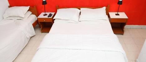 A hotel room with two single beds, each with a nightstand and a lamp.