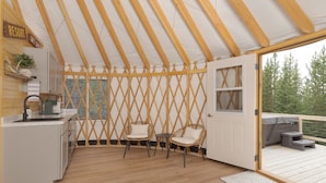 Un intérieur chaleureux avec un plafond en bois, un coin cuisine, deux fauteuils en osier et une porte donnant sur une terrasse extérieure.