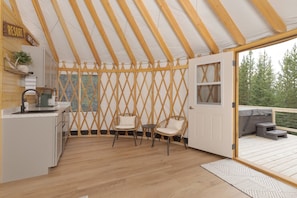 A cozy interior with a wooden ceiling, a kitchen area, two wicker chairs, and a door leading to an outdoor deck.