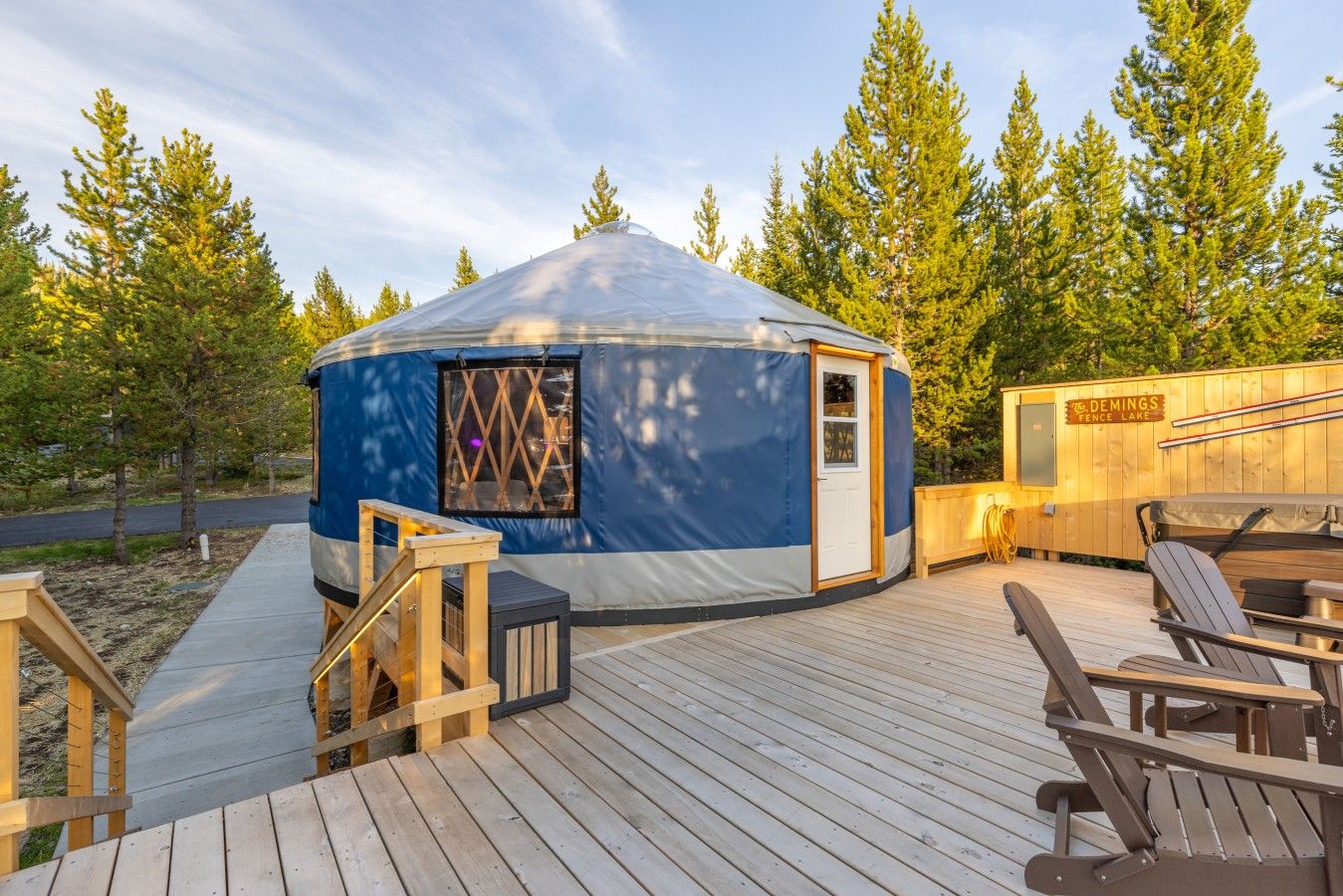 A yurt with a wooden deck, a covered seating area, and a sign indicating it's located at Fence Lake.