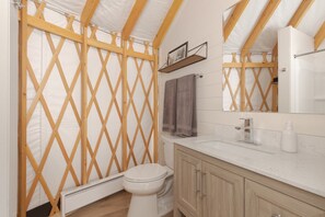 A bathroom with a wooden lattice partition, a toilet, a sink with a mirror, and a towel rack.
