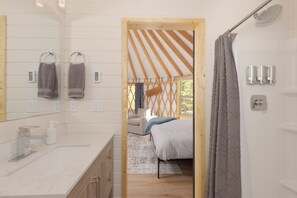 A bathroom with a large mirror, two towels, a sink, and a shower area. - Beehive Basin Yurt: Stunning Mountain Views, Private Hot Tub (Big Sky)