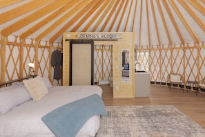 A yurt interior with a bed, a small kitchenette, and a sign reading 'Deming's Resort'.