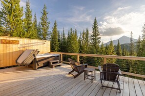 A wooden deck with a hot tub, outdoor seating, and a sign reading 'The Demings Fence Lake.' - Beehive Basin Yurt: Stunning Mountain Views, Private Hot Tub (Big Sky)