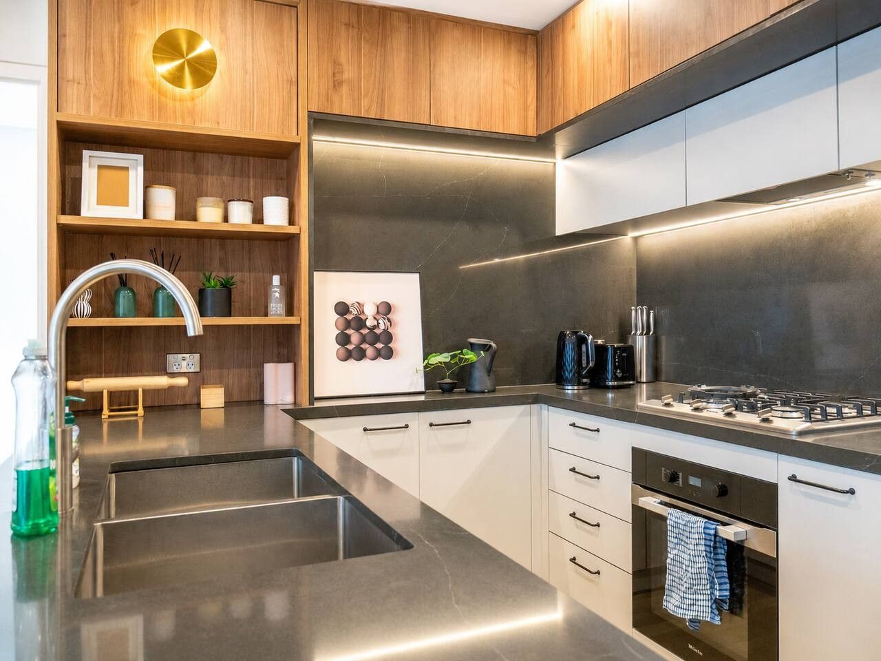 A modern kitchen with stainless steel appliances, wooden cabinetry, and a built-in oven.