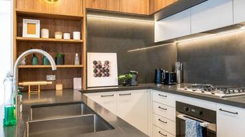 A modern kitchen with stainless steel appliances, wooden cabinetry, and a built-in oven.