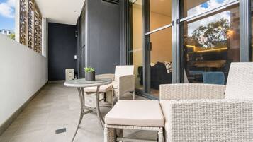 A balcony with wicker furniture, a small table, and a potted plant.