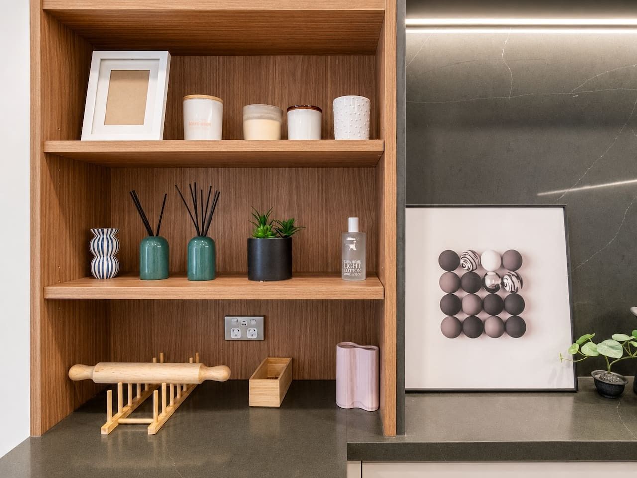 A wooden shelf with various items including a framed picture, jars, a rolling pin, and a small plant.