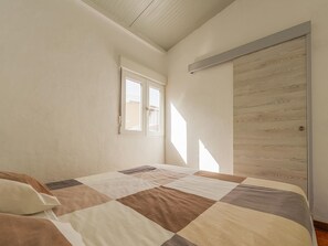 Ein Schlafzimmer mit einem Bett, einem Fenster und einer Tür.