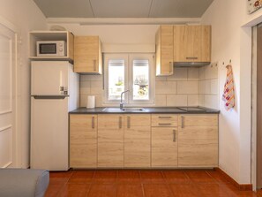 Eine kleine Küche mit integriertem Mikrowellenherd, Spüle und Holzschränken.