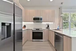 Una cocina moderna con electrodomésticos de acero inoxidable, armarios de madera y un amplio ventanal que proporciona luz natural.