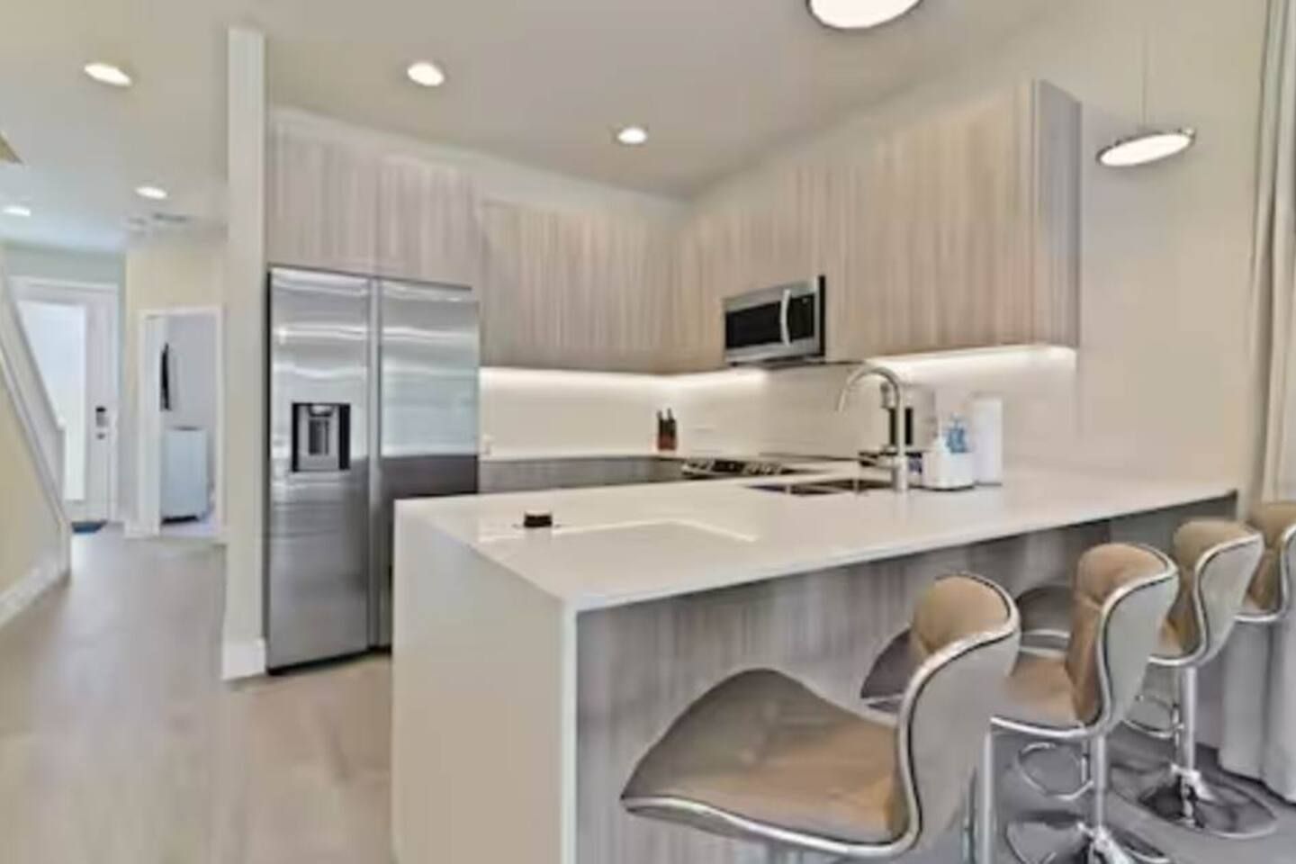 A modern kitchen with a central island, stainless steel appliances, and bar stools.