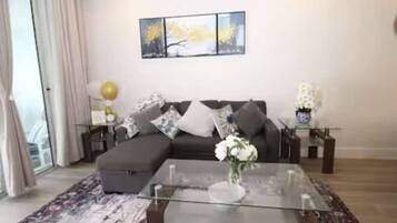 A modern living room with a sectional sofa, a glass coffee table, and a patterned rug.