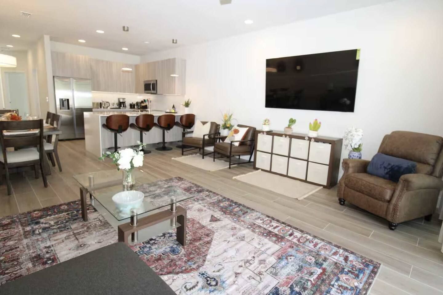 A modern living room with a glass coffee table, a sofa, and a dining area with chairs.