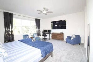 Un dormitorio con cama, escritorio, silla, cómoda y televisor.