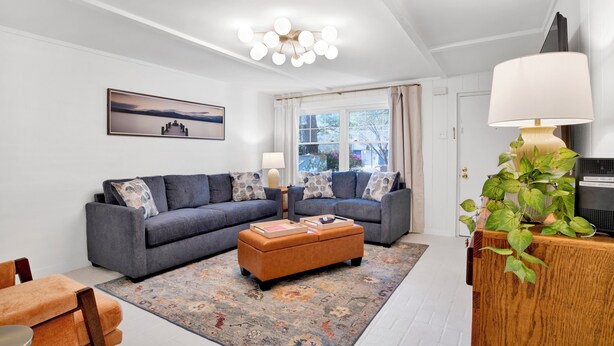 A modern living room with a grey sofa set, a patterned rug, and a wooden side table with a lamp. - Cozy 2BR Spring Hill Cottage • Pets Welcome (Mobile)