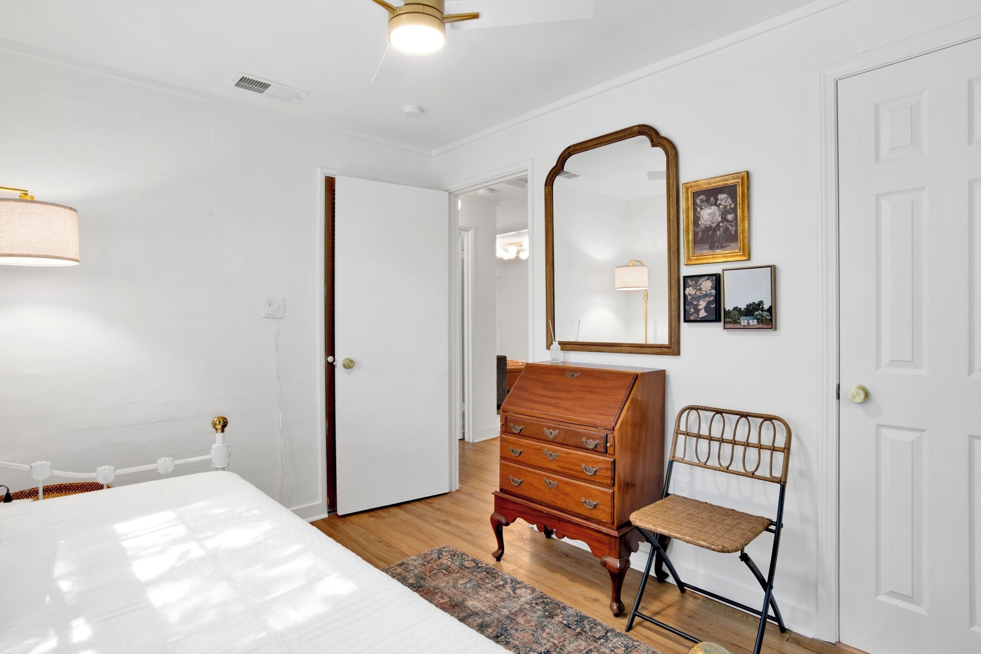 A bedroom with a bed, dresser, chair, and a large mirror.