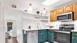 A modern kitchen with a dishwasher, oven, microwave, and a coffee maker.