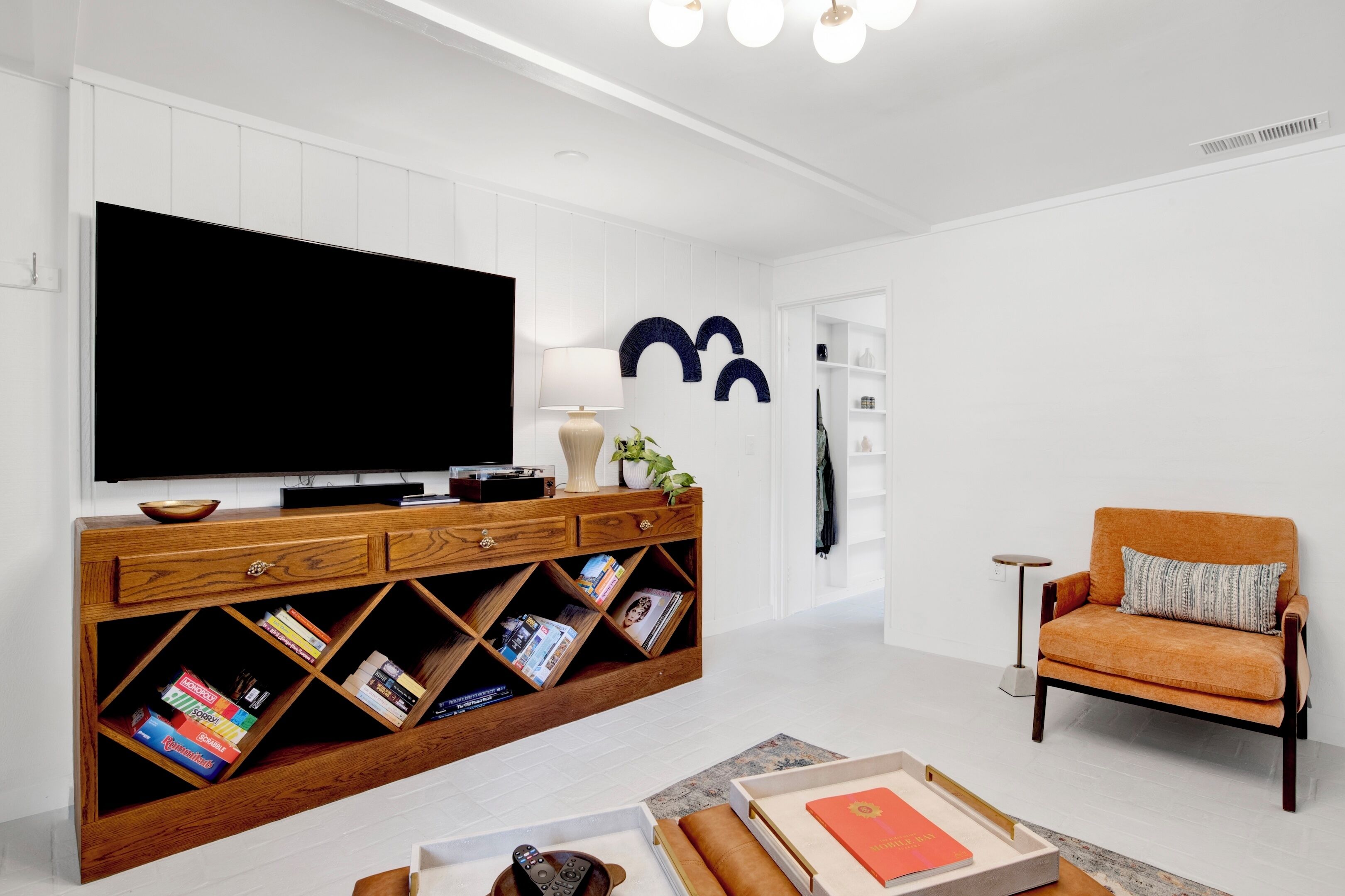 Ein modernes Wohnzimmer mit einem Flachbildfernseher, einer Holzunterhaltungsecke, Bücherregalen, einer Couch und einem kleinen Beistelltisch.