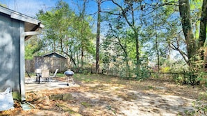 A backyard with a barbecue grill, a covered seating area, and a wooden fence.