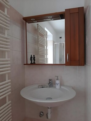 A bathroom with a white sink, a mirror, and a towel rack.