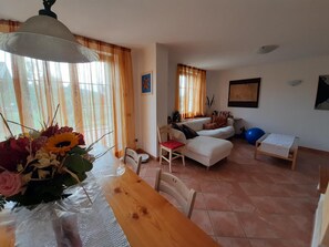 A living room with a dining table, sofa, and a small table with a chair.