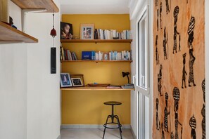 Ein Flur mit Bücherregal, einem kleinen Hocker und einer Wand mit Stammeskunst.