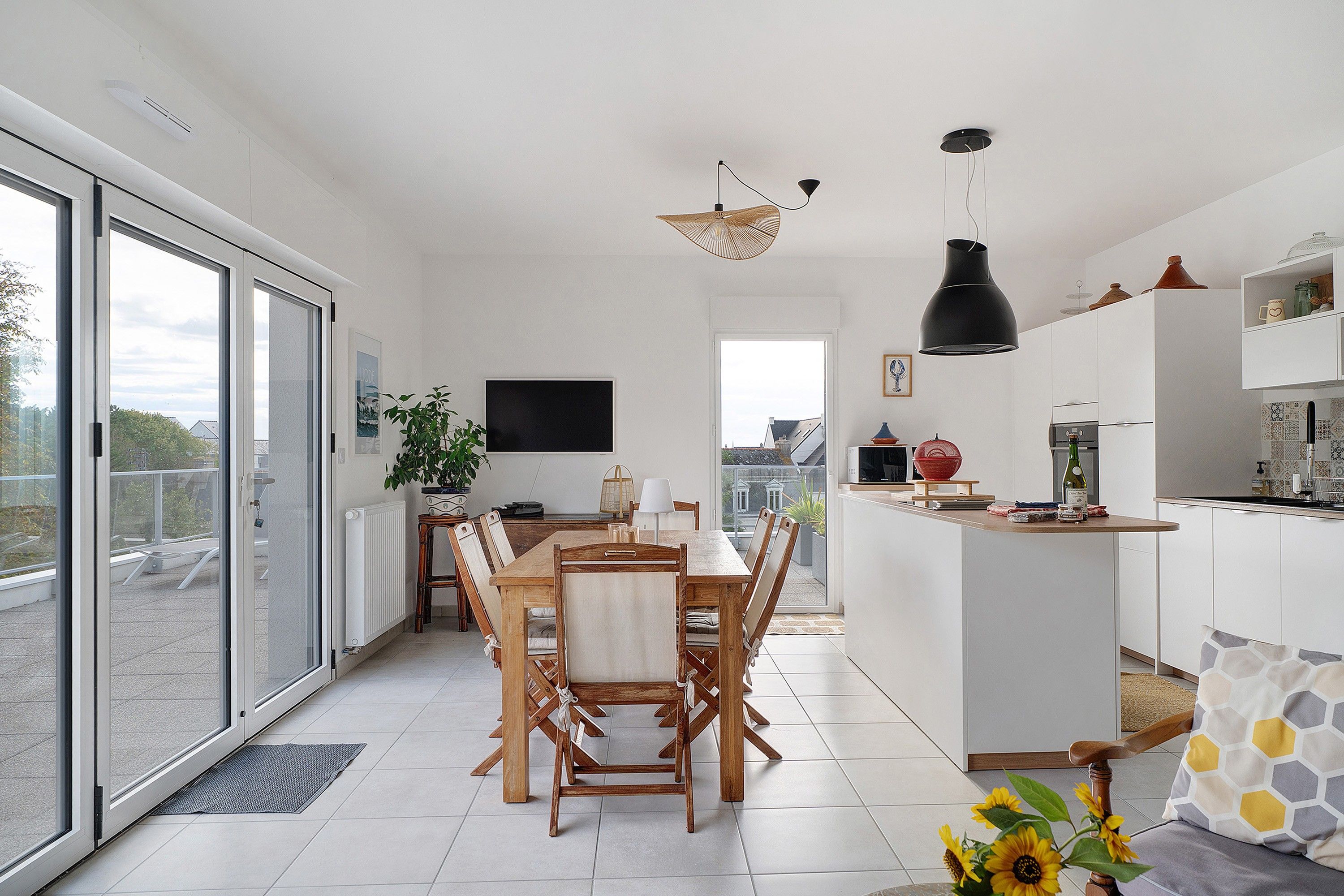 A modern kitchen with a dining area, large windows, and a view of the city.