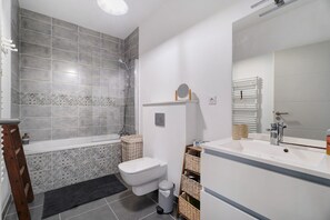 Et moderne badeværelse med badekar, toilet og håndvask.