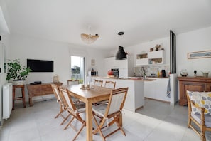 Eine moderne Küche mit weißen Schränken, ein Essbereich mit Holzmöbeln und ein großes Fenster für natürliches Licht.