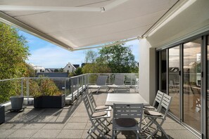 Ein Balkon mit Gartenmöbeln, einer Pergola und Blick auf die Stadtlandschaft.