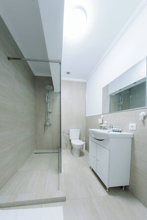 Un baño moderno con ducha envuelta en vidrio, inodoro y tocador con espejo.