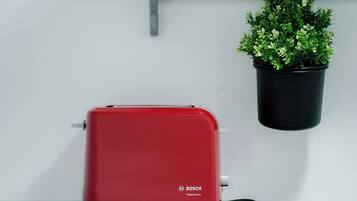 Un tostador rojo Bosch sobre una encimera blanca con una planta en maceta colgante.