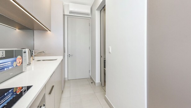A modern kitchen with a built-in microwave, a sink, and a door leading to another room. - Refined City Living with Panoramic Views (Johannesburg)