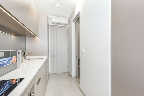 Een moderne keuken met een ingebouwde magnetron, een spoelbak en een deur naar een andere kamer.