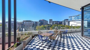 A rooftop terrace with a checkered floor, seating, and a city view. - Refined City Living with Panoramic Views (Johannesburg)