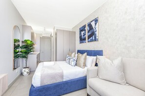Ein modernes Schlafzimmer mit einem Bett, einer Couch, einem Spiegel und zwei Wandbildern.